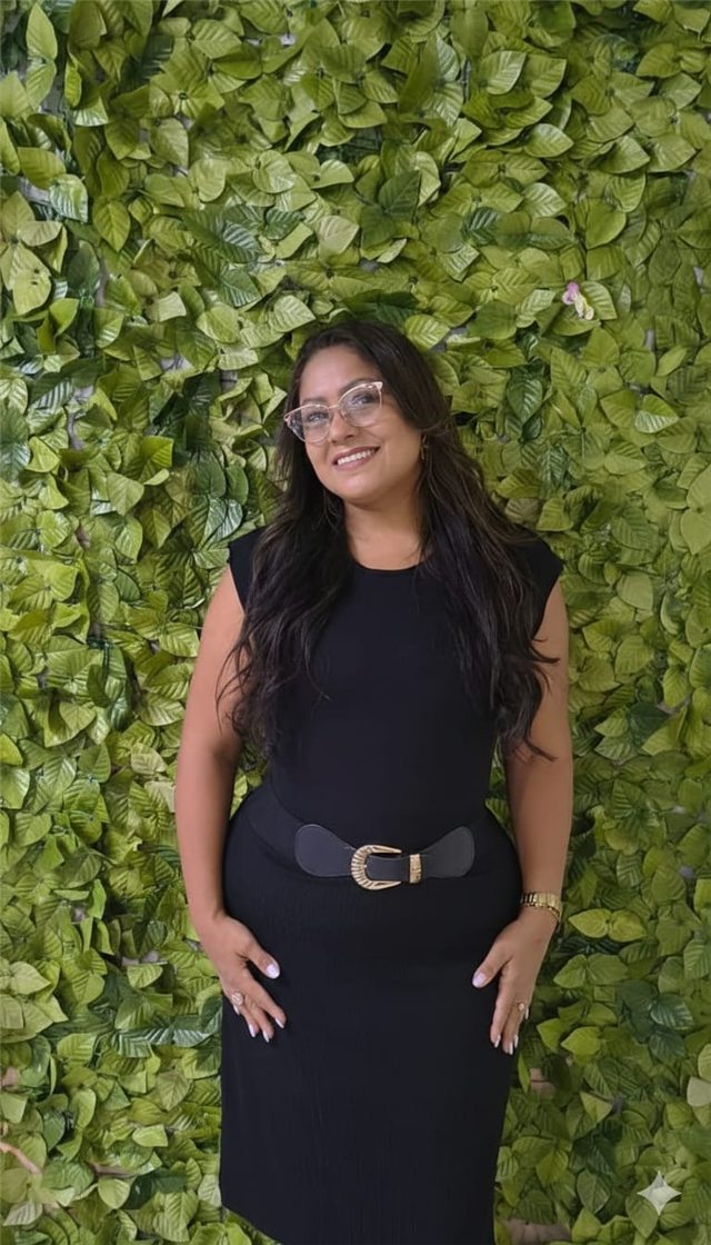 Retrato de Lílian Cristina sorrindo diante de uma parede de folhagem